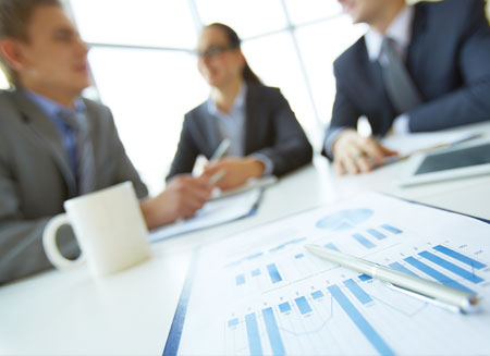 Two men and a woman sit at a conference table smiling and discussing their association shipping program.