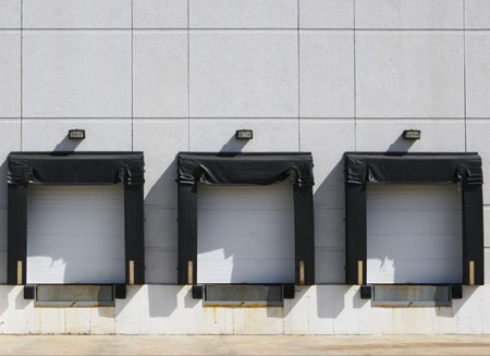 Three warehouse loading dock doors waiting for inbound shipping.