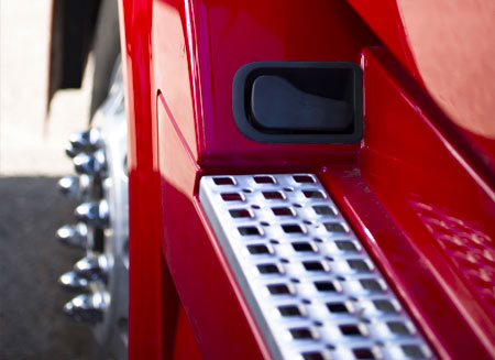 Close-up of a shiny chrome truck step on a red cab.